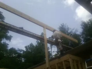 Carpenter setting a ridge beam over a new addition frame — Ice Dam Removal by Roofing Brothers in Americus