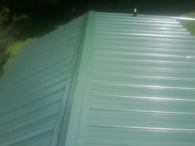 New green metal panels meeting at the ridge of a roof — Flat Roof Repair work by our crew in Americus