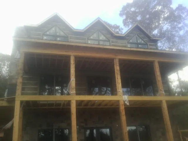 Dormers and porch framing on a large log home under construction — Roof Coating work by our crew in Americus