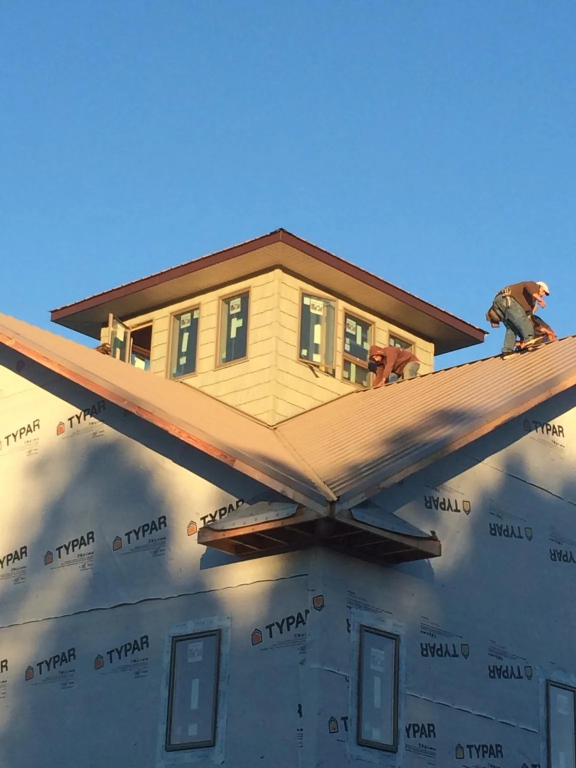 Roofers working around a rooftop cupola on a new metal roof at sunset — Roof Waterproofing in Americus by Roofing Brothers